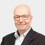 Porträtfoto eines Mannes mit grauen kurzen Haaren, Bart und Brille