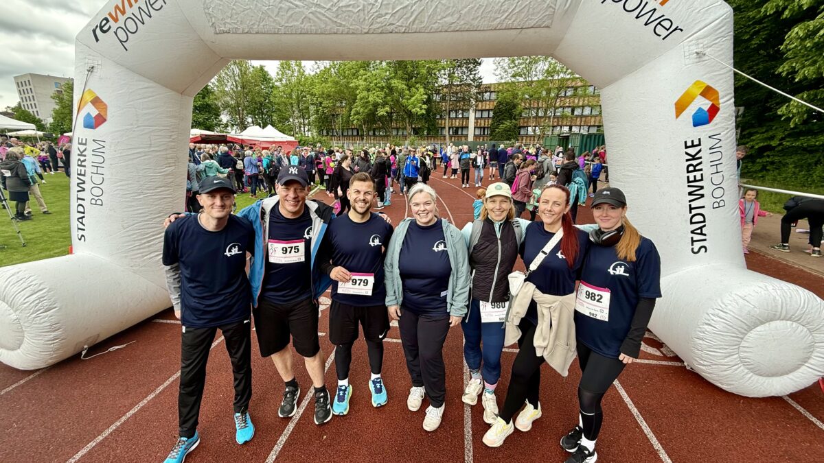 Gruppenfoto von sieben Mitarbeitenden der ARGE Krebs in Laufkleidung vor dem Start des Bochumer Brustkrebslaufs 2025.