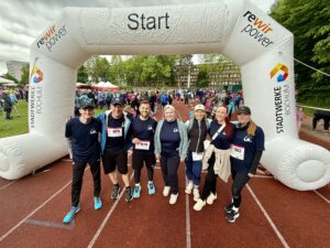 Gruppenfoto von sieben Mitarbeitenden der ARGE Krebs in Laufkleidung vor dem Start des Bochumer Brustkrebslaufs 2025.