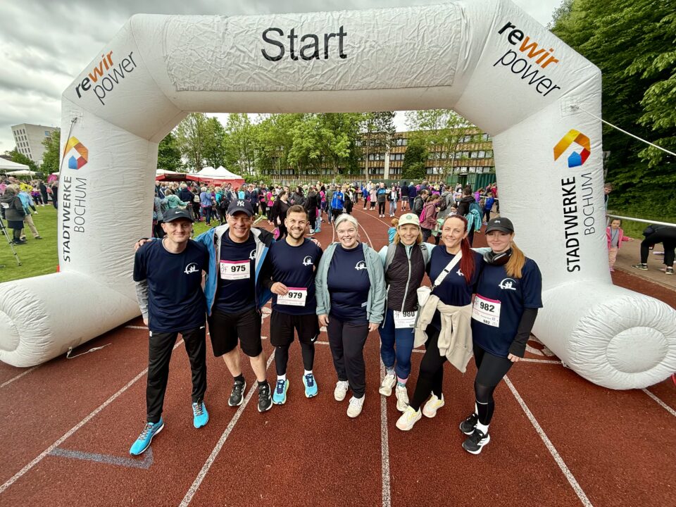 Gruppenfoto von sieben Mitarbeitenden der ARGE Krebs in Laufkleidung vor dem Start des Bochumer Brustkrebslaufs 2025.