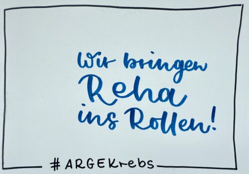 Handgeschriebene Karte mit dem Spruch „Wir bringen Reha ins Rollen – ARGE Krebs“.