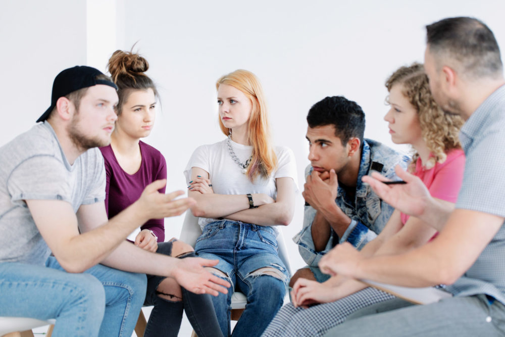 Junge Erwachsene im Stuhlkreis während einer Gruppentherapie