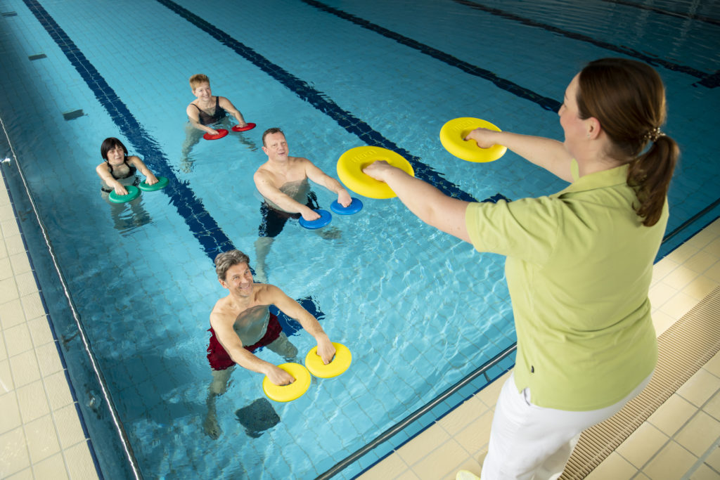 Zwei Männer und zwei Frauen bei der Wassergymnastik mit Trainerinungsbad
