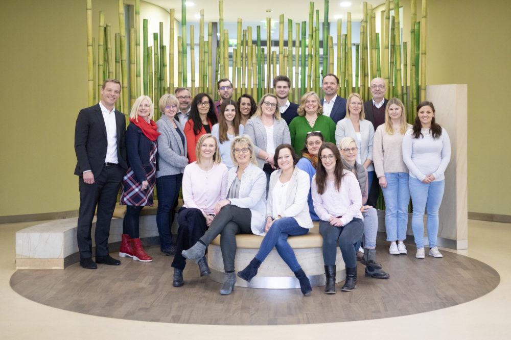 Gruppenbild zeigt Mitarbeiterinnen und Mitarbeiter im Foyer der Geschäftsstelle