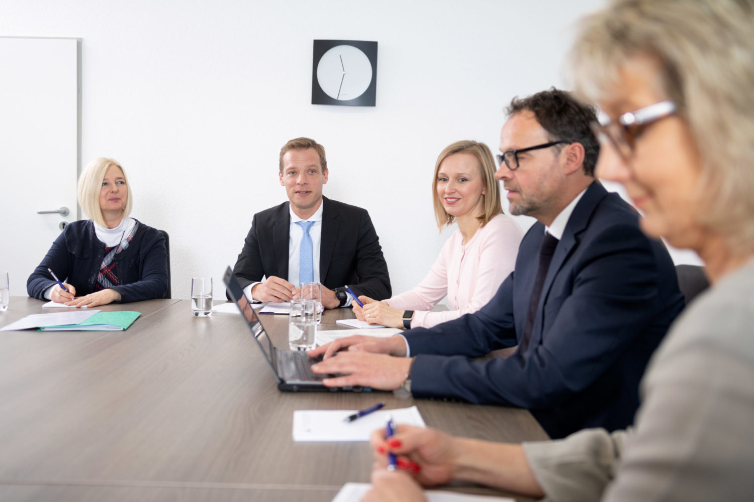 Drei Frauen und zwei Männer sitzen an einem Besprechungstisch