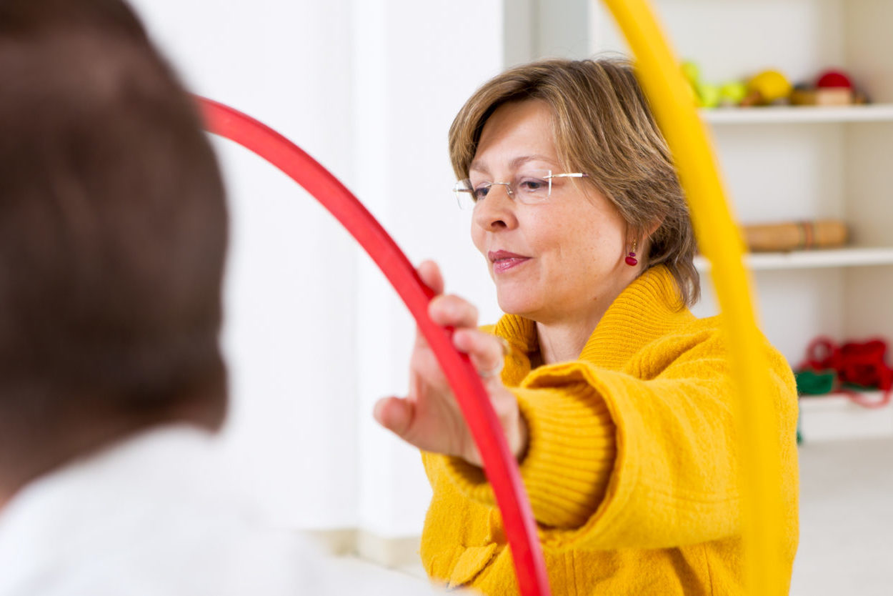 Frau im gelben Pullover greift nach einem roten Hula-Hoop-Reifen